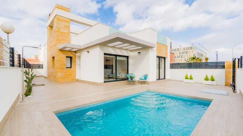 A contemporary villa and its pool, under a clear sky.