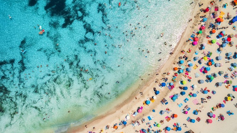A Costa Blanca beach seen from above, parasols lined up on the sand.
