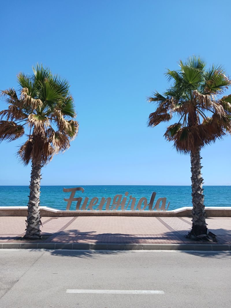 The Fuengirola sign on the seafront, between two palm trees